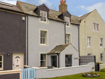 Row of attached houses with small front yards and a blue gate at Gulls Hatch in Allonby