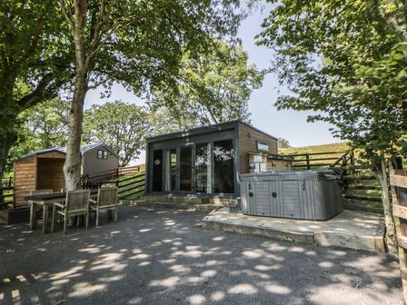 An outdoor area with a hot tub and seating at The Fox Den in Nantmel near Rhayader
