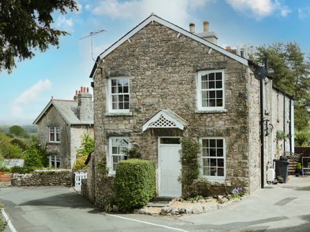 A stone house with white framed windows and a white door at Mount Pleasant Cottage in Lindale near Grange-over-Sands