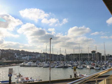 A marina with boats and yachts docked and buildings in the background at Harbourside Haven Apartment 1 in Weymouth