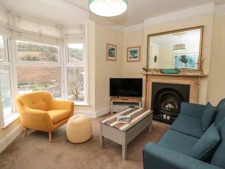 A living room with a yellow armchair a blue sofa a coffee table a television and a fireplace at 5 Fairview Road in Dartmouth