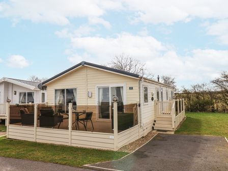 A single-story mobile home with enclosed porch furniture and a small driveway at Two Little Ducks in Cayton