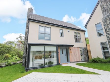 A modern two-story house with large windows and a grassy front yard at Summer Rose in Craster