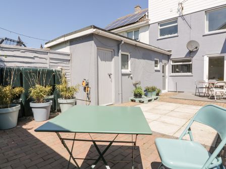 An outdoor patio area with a green table and chair potted plants on a paved floor at Eloen in Crantock