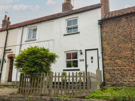 A white cottage with two chimneys and a small fenced front garden with a bush at Ascot Cottage Sheriff Hutton near Strensall