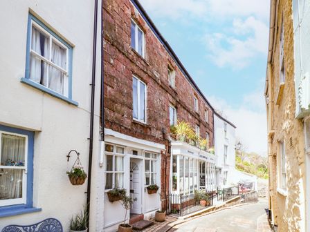A narrow street with stone and white buildings with windows and potted plants at Garretts in Kingsand And Cawsand