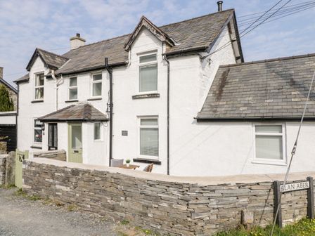 A stone walled white house with multiple windows and a green door at Cooper's Rest Gorffwysfa Coopers in Dolwyddelan
