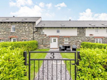 Stone cottage with a gated front garden and outdoor seating at Ty Bach Twt in Valley