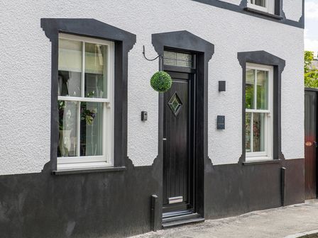 Front view of a house with black door and white framed windows at The Old Sweet Shop in Conwy
