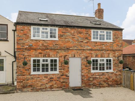 A brick house with white framed windows and a central door at New Inn Apartment in Tholthorpe near Easingwold