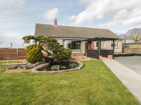 The front of a bungalow with a garden pond bench and a walkway at The Croft Bungalow in Plumbland near Aspatria