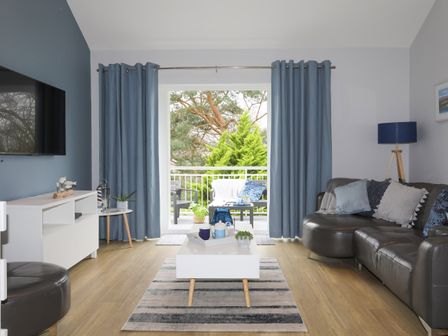 A living room with a sofa a coffee table TV and blue curtains at Anchors Rest in Y Felinheli