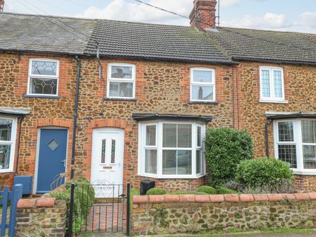 Stone terraced houses with white and blue doors and bay windows with bushes in front at Hunny Cottage in Hunstanton