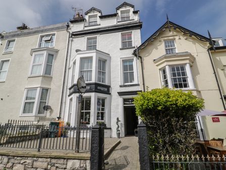 A row of three attached buildings with a hairdressing salon and garden area at Llewelyn Apartment in Llandudno
