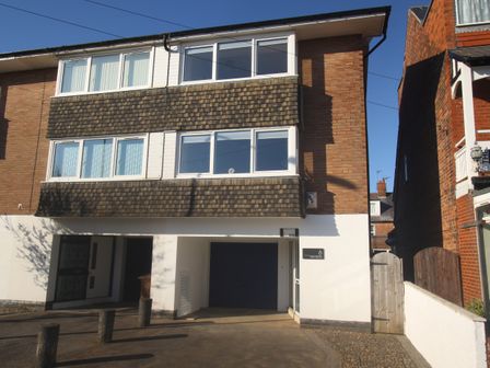 A three story brick and white building with multiple windows and a garage door at Sea Mews in Bridlington