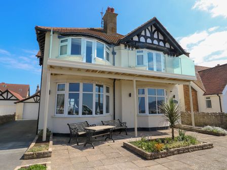 A two-story house with bay windows a balcony benches and a small garden in front at Westbourne in Llandudno