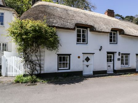 A thatched roof cottage with white walls and multiple windows and doors at Small Piece in Porlock