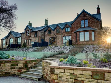 A stone house with multiple windows and chimneys with stairs and garden in front at Tarn End Cottages 8 Talkin Tarn near Brampton Cumbria