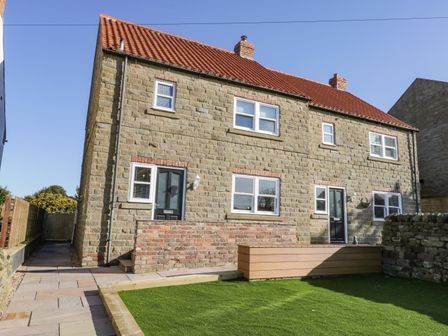 Stone house with red tiled roof two black doors several windows and artificial grass lawn at Old Peak in Ravenscar near Cloughton