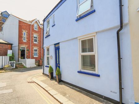 A street view of blue and red brick houses with windows and a blue door with plants outside at Lake Victoria Cottage in Dartmouth