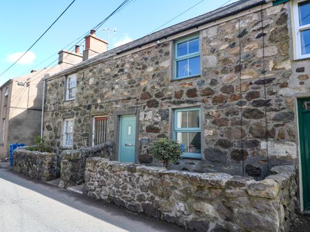 Stone house with blue doors and windows and a small stone wall along the street at Ferndale in Llanbedrog