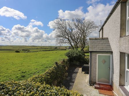 A view of a green field with a tree next to a house entrance at Tregynrig Bach in Cemaes Bay