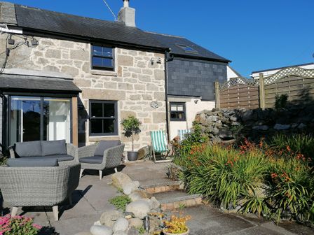 A stone cottage with an outdoor seating area and garden at Trenwith Bridge Cottage in St Ives