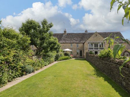 A stone house with a garden lawn and stone wall and green plants at Little Owl Barn in Burford
