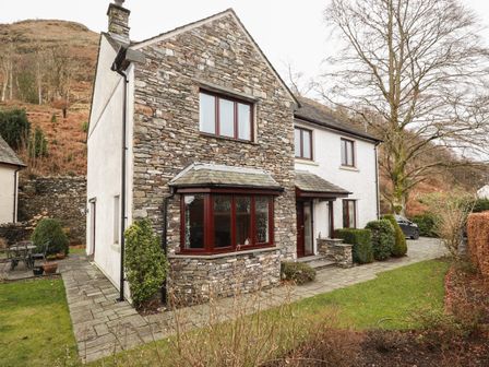 A stone and white exterior house with windows a driveway and garden at Beech Nook in Thornthwaite