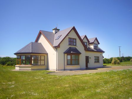 A detached house with multiple windows and a grassy lawn at Tra Gheal in Kilmore County Wexford