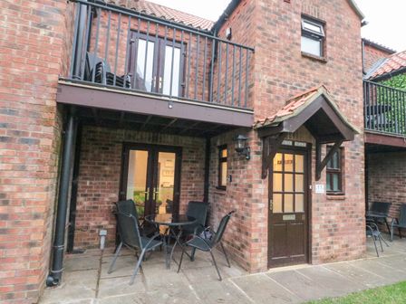 A brick house exterior with a balcony a patio table and chairs at Herons Reach in Whitby