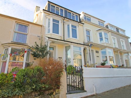 A row of terraced houses with bay windows and a gated entrance at Brynmor in Borth-y-Gest near Porthmadog