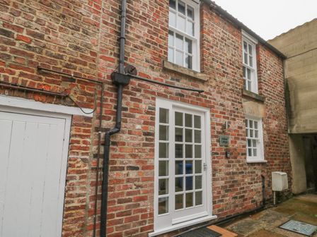 Brick exterior wall with white framed windows and door at Ashben Cottage in Whitby