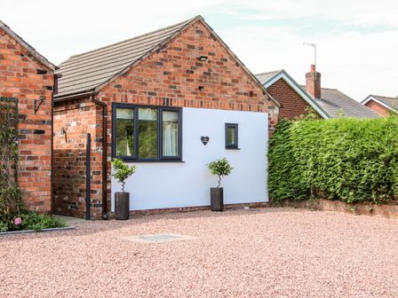The exterior of a brick house with two potted plants and gravel in front at Oakleigh in Four Crosses