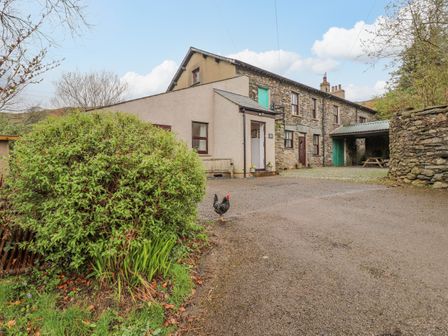 A farmhouse with a gravel driveway a chicken bushes and a covered seating area at The Stables in Broughton-In-Furness near Thwaites