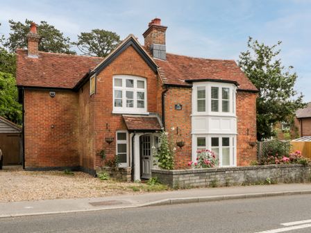 A brick house with white windows and a tiled roof by a roadside at Oakapple Cottage in Swan Green near Lyndhurst