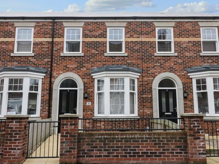 The front of two brick townhouses with black doors and white framed windows at Stone's Throw in Filey