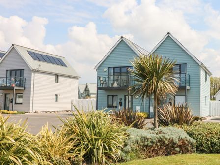 Two modern houses with balconies and solar panels surrounded by plants and a lawn at Seaquel in Westward Ho