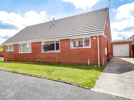 A red brick house with a sloped roof driveway and garage at 22 Gwel Yr Wyddfa in Menai Bridge