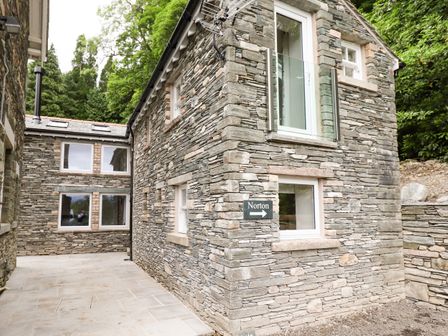 A stone exterior of a building with several windows and a sign reading Norton surrounded by trees at Norton in Applethwaite