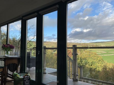 A dining area with flowers on a table and an outdoor view at The Sett on the Wharfe in Skipton