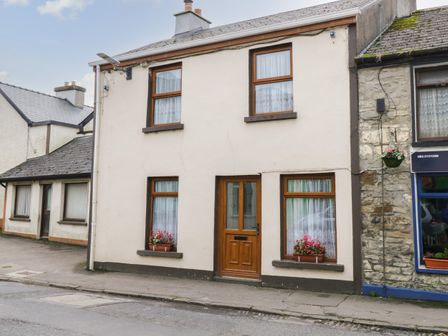 A two-story house with wooden framed windows and a wooden door with flower pots on the windowsills on a street at Georges Street in Killala County Mayo