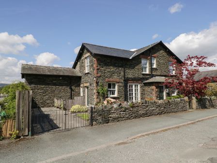 A stone house with a stone wall driveway and red tree at Silverthwaite in Windermere
