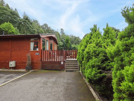 An outdoor view of a lodge with a wooden deck at Birthwaite Lodge, Fellside 6, Limefitt Park near Windermere
