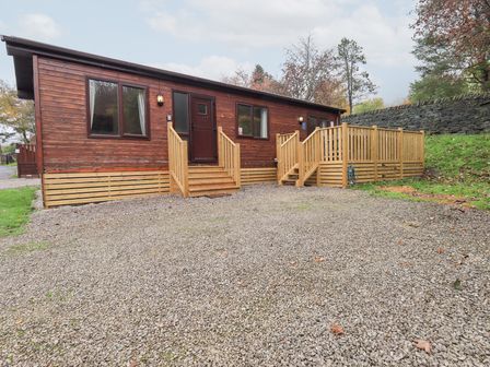 A wooden cabin with steps and a gravel driveway at Robin View Lodge, Beckside 3, Limefitt Park near Windermere