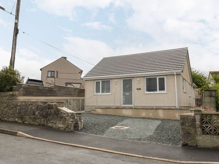 A detached house with a gravel driveway and stone wall at Trigfa in Llanfechell
