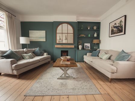 A living room with two beige sofas a wooden coffee table a fireplace with a mirror above it and built in shelves at Fairhaven in Dartmouth