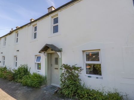 Exterior view of a row of connected white cottages with multiple windows and a central door at Fellside Cottage in Embleton near Keswick