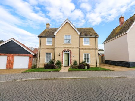 A detached house with a green front door and two windows on each side with a double garage on the left at Coral House in Overstrand