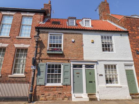 A street view of connected brick and white painted houses with red tiled roofs and green doors at Bobbies' Retreat 20 High Street Bridlington